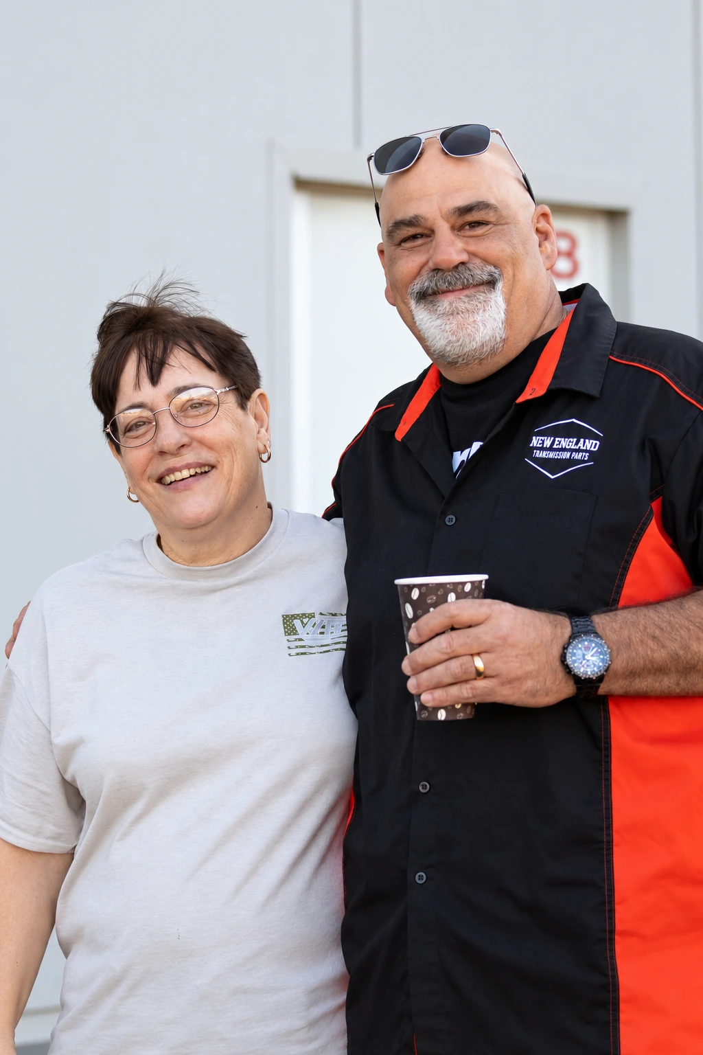 Two people smiling outside the building.